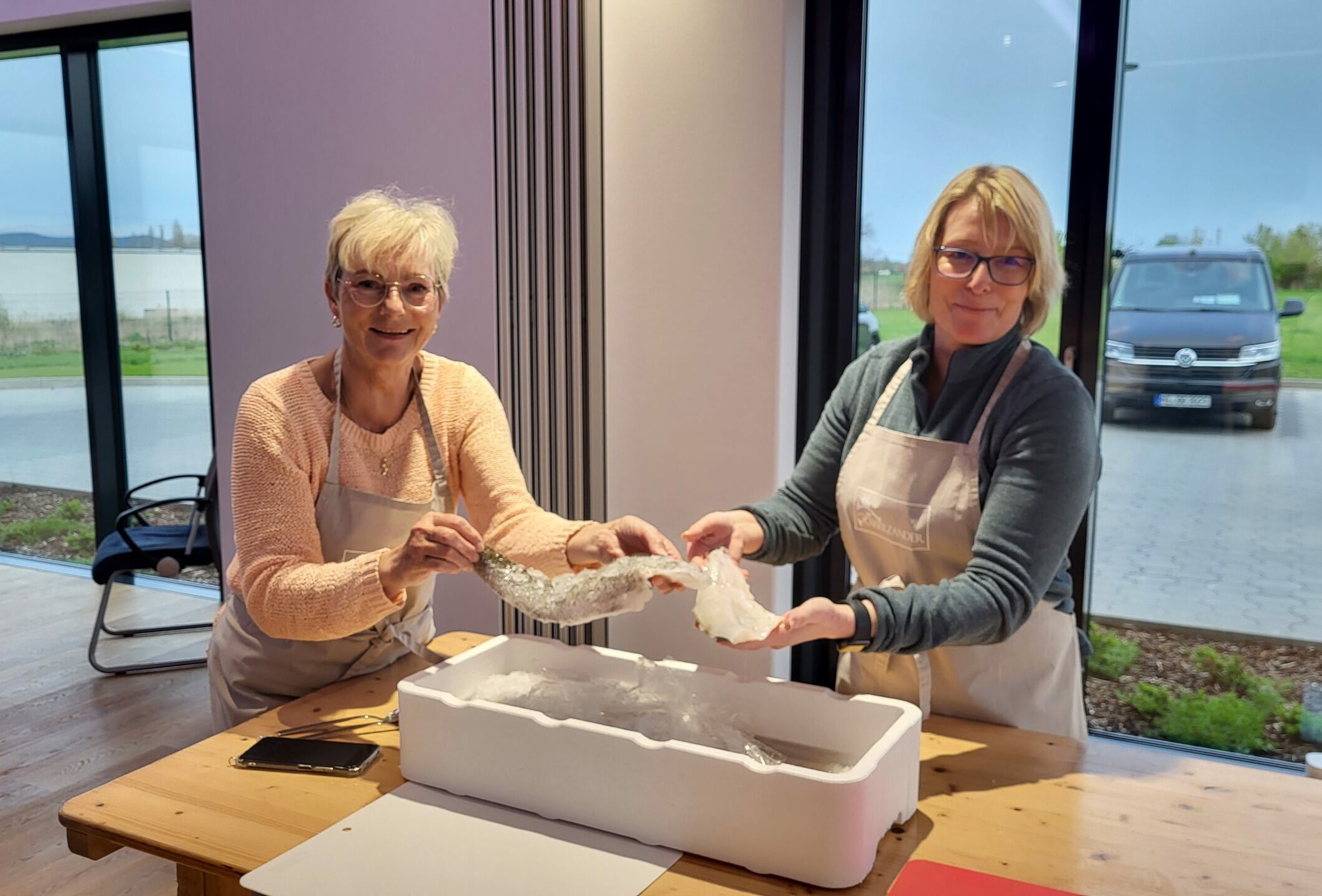 Bild von zwei Frauen, die ein Fischfilet in die Kamera halten