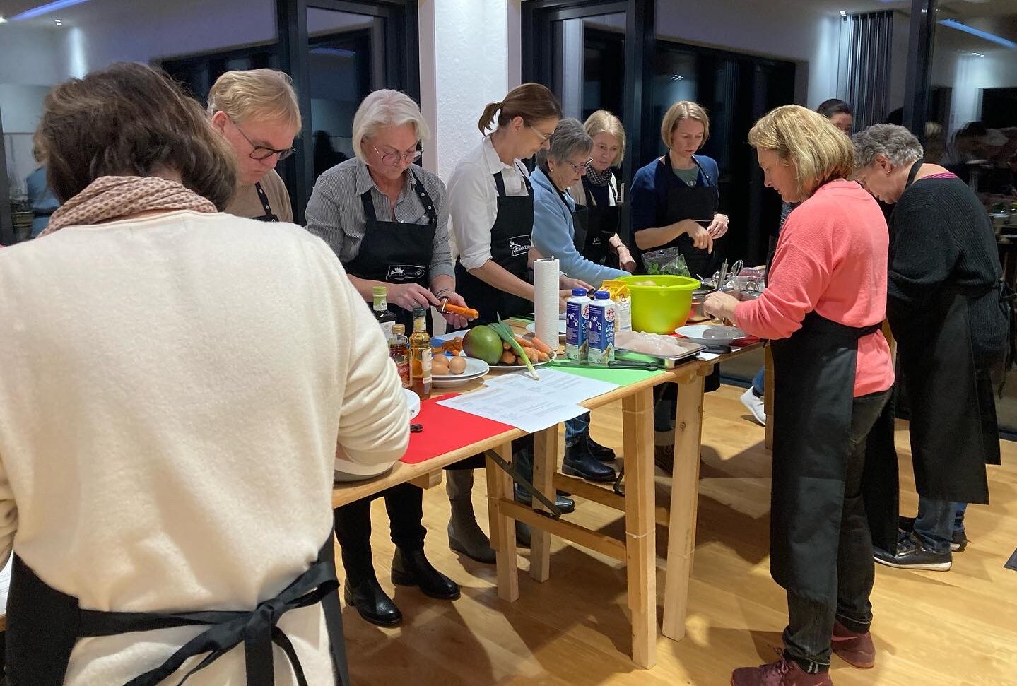 Bild von Menschen, die um einen Tisch stehen und zusammen kochen